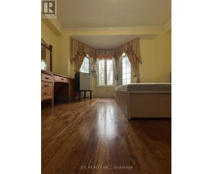 A bedroom with a bed, dresser, and window.
