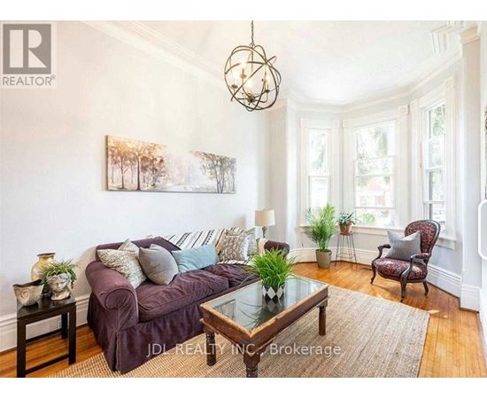 A living room with a purple couch, a glass table, and a painting on the wall.