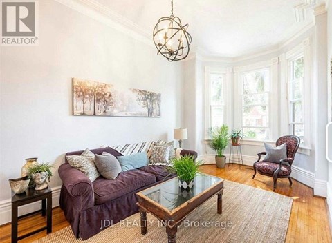 A living room with a purple couch, a glass table, and a painting on the wall.