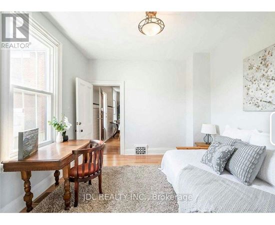 A bedroom with a bed, a table, and a chair.