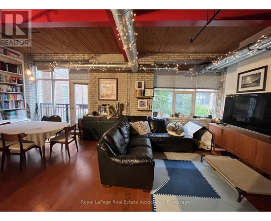 A living room with a black leather couch and a television.