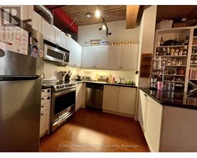 A kitchen with white cabinets and a stainless steel refrigerator.