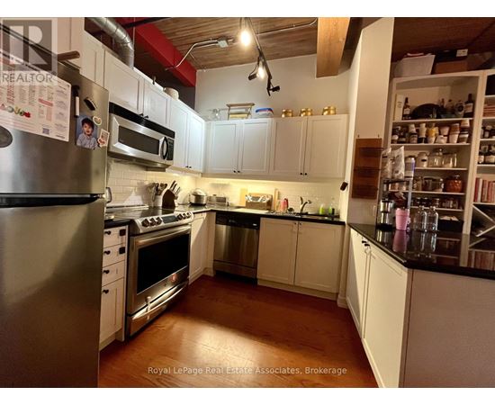 A kitchen with white cabinets and a stainless steel refrigerator.