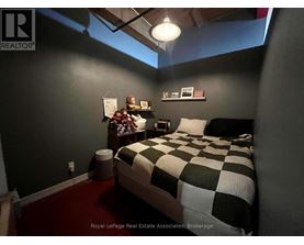 A bedroom with a bed, nightstand, and pictures on the wall.