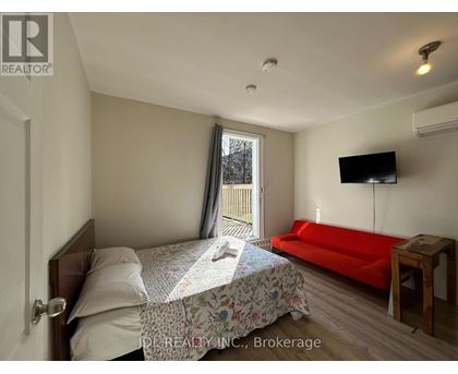 A bedroom with a bed, a couch, and a television.