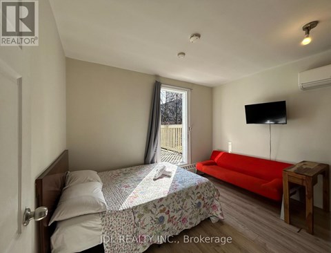 A bedroom with a bed, a couch, and a television.