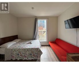 A bedroom with a bed, a sofa, and a television.