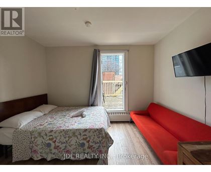 A bedroom with a bed, a sofa, and a television.