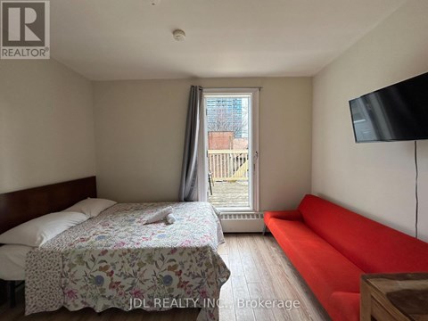 A bedroom with a bed, a sofa, and a television.