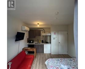 A small room with a red couch and a bed with a floral bedspread.