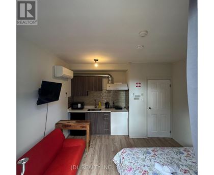 A small room with a red couch and a bed with a floral bedspread.