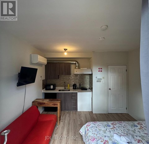 A small room with a red couch and a bed with a floral bedspread.