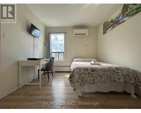 A bedroom with a bed, desk, chair, and window.
