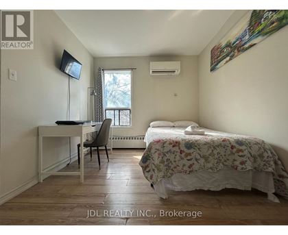 A bedroom with a bed, desk, chair, and window.