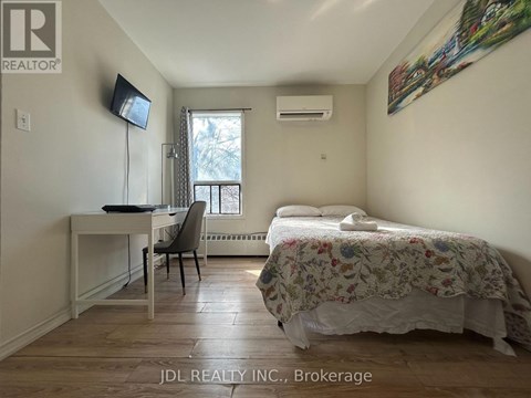 A bedroom with a bed, desk, chair, and window.