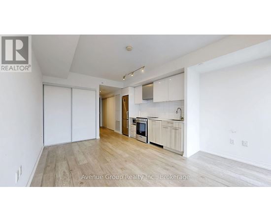 A spacious kitchen with white cabinets and a wooden floor.