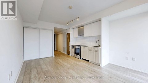 A spacious kitchen with white cabinets and a wooden floor.