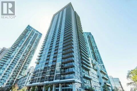 A tall residential building with a glass facade stands in front of two other buildings.