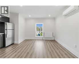 A spacious empty room with a fridge and a window.