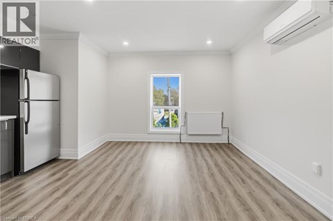 A spacious empty room with a fridge and a window.