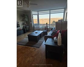 A living room with a couch, ottoman, and a fan.
