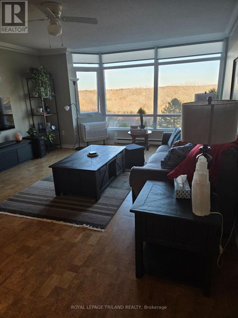 A living room with a couch, ottoman, and a fan.