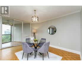 A dining room with a glass table and grey chairs.