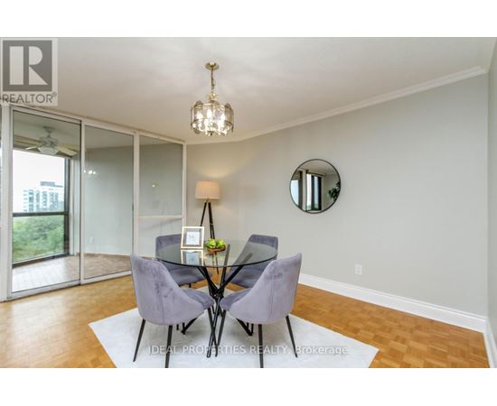 A dining room with a glass table and grey chairs.