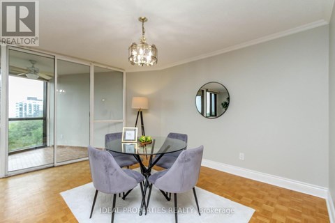 A dining room with a glass table and grey chairs.