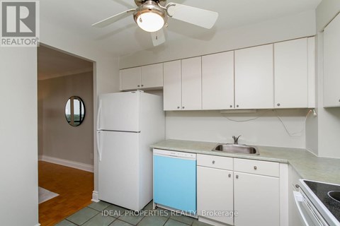 A small kitchen with white cabinets and a blue dishwasher.