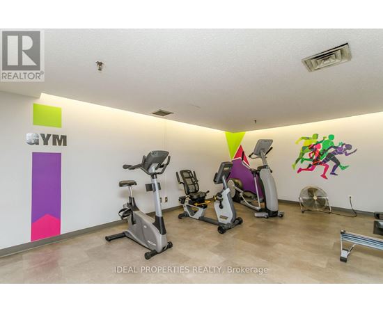 A gym with exercise equipment and a wall with a colorful design.