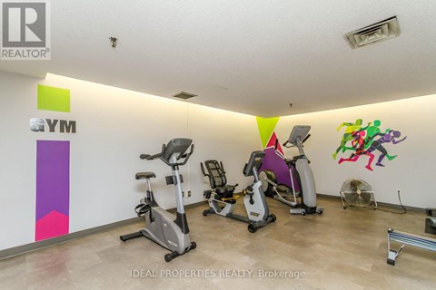 A gym with exercise equipment and a wall with a colorful design.