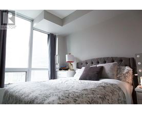 A bedroom with a large bed and a window with curtains.