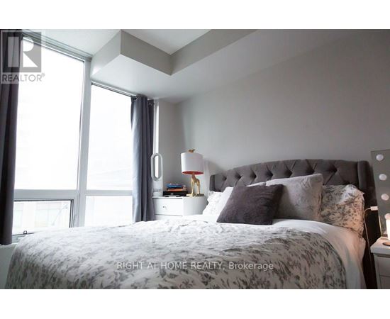 A bedroom with a large bed and a window with curtains.