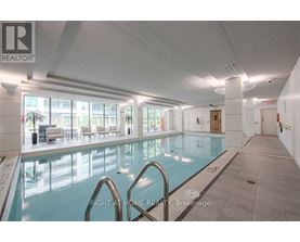 A large indoor swimming pool with a glass wall and a diving board.