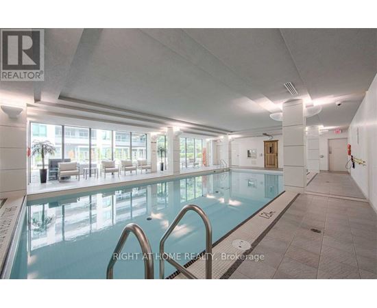 A large indoor swimming pool with a glass wall and a diving board.