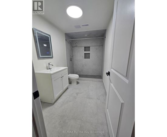 A bathroom with a toilet, sink, and mirror.