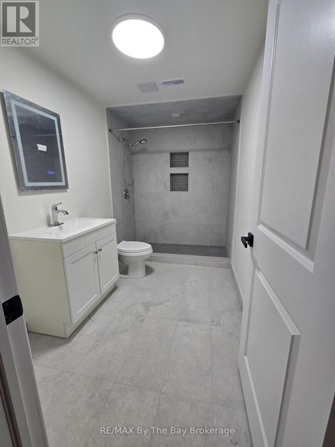 A bathroom with a toilet, sink, and mirror.