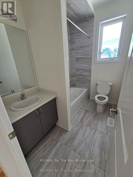 A bathroom with a toilet, sink, and a window.