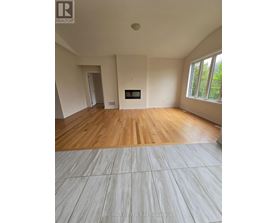 A room with wooden flooring and a fireplace is shown.