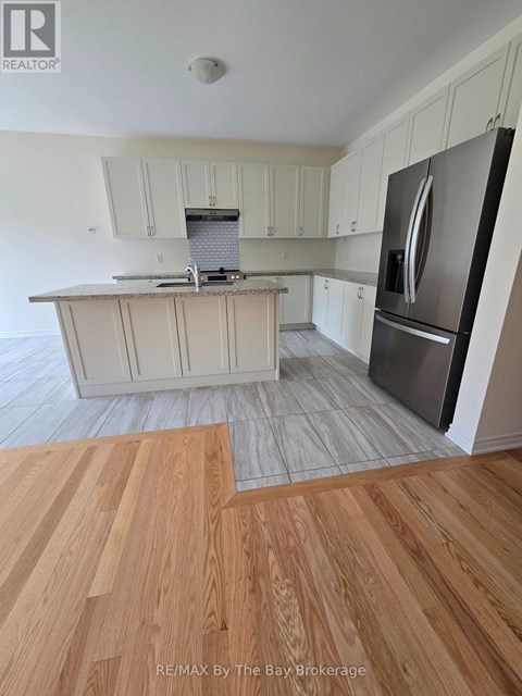 A kitchen with white cabinets and a stainless steel refrigerator.