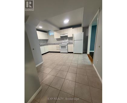 A kitchen with white appliances and cabinets in a room with tiled flooring.