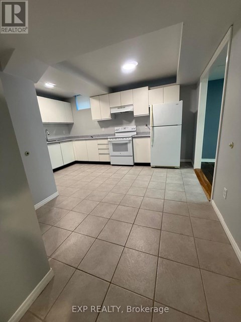 A kitchen with white appliances and cabinets in a room with tiled flooring.