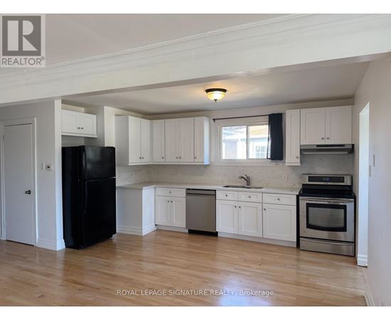 A kitchen with white cabinets and a black fridge.