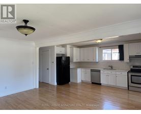 A kitchen with white cabinets and a black refrigerator.