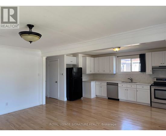 A kitchen with white cabinets and a black refrigerator.