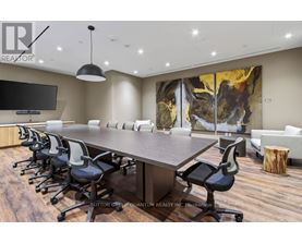 A conference room with a long table and chairs, a television, and a large abstract painting on the wall.
