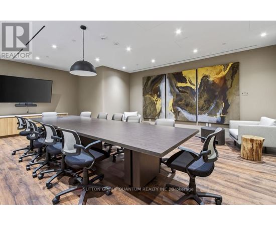 A conference room with a long table and chairs, a television, and a large abstract painting on the wall.