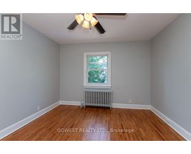 A room with a ceiling fan and a window with a view of trees.