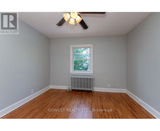 A room with a ceiling fan and a window with a view of trees.